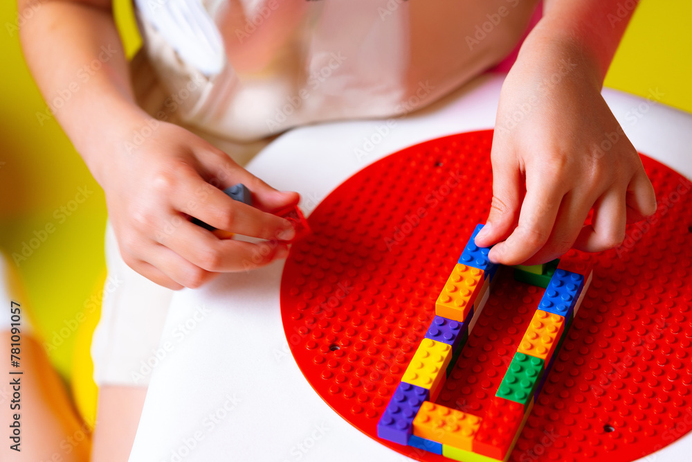Poster child engaged in creative play with colorful building blocks on a round base