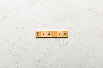 EVOLVE word written on wood block. EVOLVE text on cement table for your desing, concept