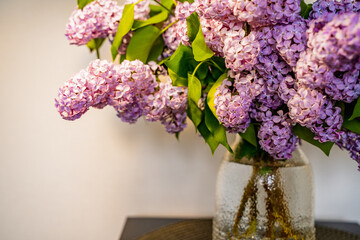lush bouquet of lilacs on a black table in a transparent jar - obrazy, fototapety, plakaty