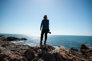 Woman photographer enjoy the view on sunrise seaside rocks - Powered by Adobe