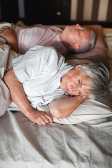 Sad seniors couple in bed at home