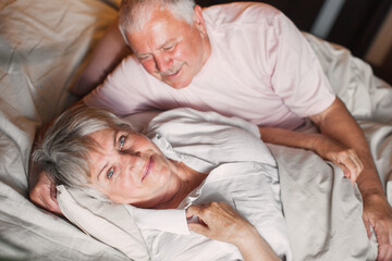 Happy elderly couple wakes up in bed in the morning - 781102668