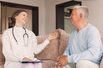 Female professional doctor showing medical test result explaining prescription using clipboard visiting senior elderly old man patient at home sitting on sofa - 781102884