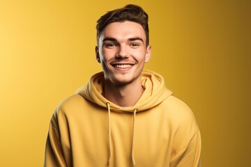Obraz premium A young man is smiling and wearing a yellow hoodie
