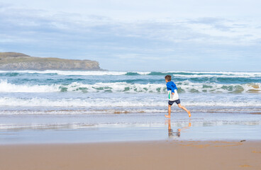 Boy running on the shore of a beach without people