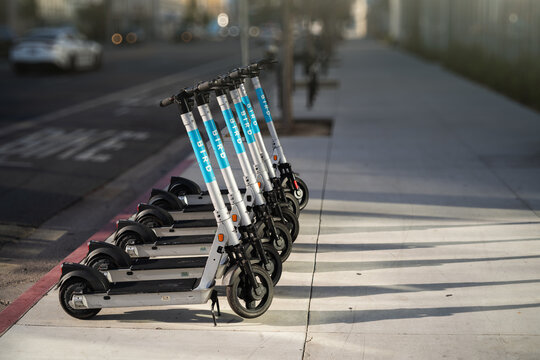 LOS ANGELES - April 7, 2024: Electric scooters sharing ready for a ride lined up on empty city street.