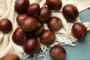 Roasted edible sweet chestnuts on light blue wooden table, flat lay