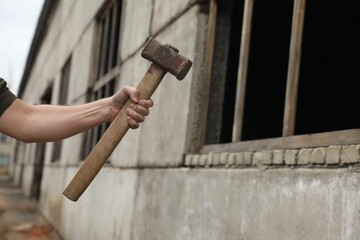 Man with sledgehammer near old building outdoors, closeup. Space for text