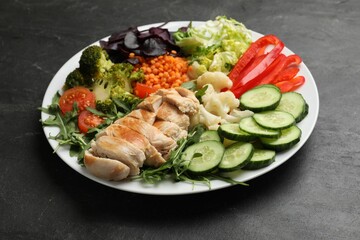Balanced diet and healthy foods. Plate with different delicious products on black table