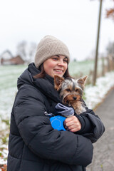 Young woman with yorkshire terrier dog in a winter park.