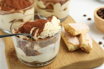 Delicious tiramisu in glasses, cookies and spoon on white table, closeup