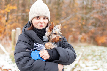 Young woman with a Yorkshire Terrier dog in the park in winter