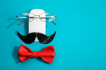 Flat lay composition with artificial moustache and glasses on light blue background, space for text