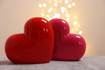 Ceramic hearts on grey table against blurred lights