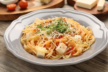 Vegetarian meal. Tasty pasta with fresh microgreens and cheese on wooden table, closeup