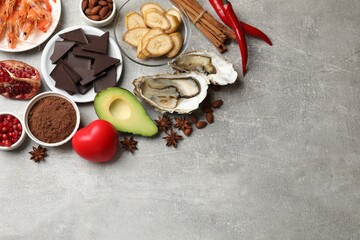 Fototapeta na wymiar Natural aphrodisiac. Different food products and heart model on grey table, flat lay. Space for text