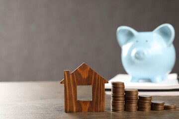 House model, stacked coins and piggy bank on wooden table, selective focus. Space for text © New Africa
