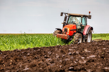 Tractor cultivating fertile soil on a sunny day, preparing the land for the upcoming planting season