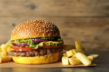 Burger with delicious patty and french fries on table, closeup