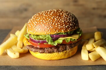 Burger with delicious patty and french fries on table, closeup