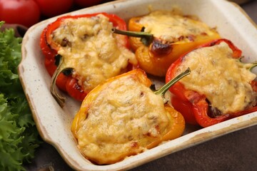 Delicious stuffed peppers in baking dish on brown table, closeup