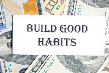 BUILD GOOD HABITS motivational concept text on a white business card against the background of money, a business concept
