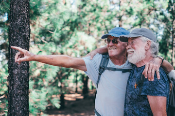 Happy senior couple of men smiling enjoying a mountain hike in the forest appreciating leisure and freedom, active cheerful retired seniors and healthy lifestyle concept