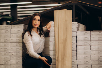  Portrait of young woman choosing wood laminated flooring in shop