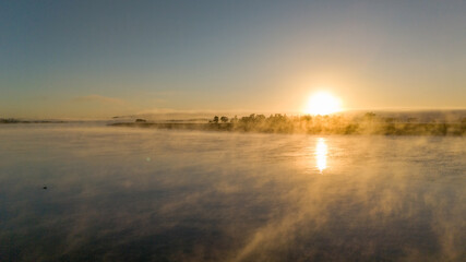 Mist rising over a river a sun rise.