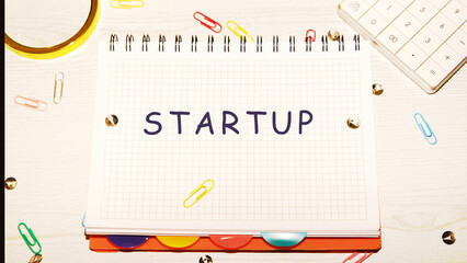 Startup - word concept on a notebook in a cage on the table