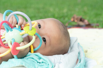 Esther Title: Infant Baby Girl is laying on her back in a pink bodysuit with a development toy for teething.