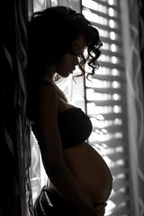 Fototapeta na wymiar A close-up intimate shot accentuating the curves of a pregnant woman's abdomen