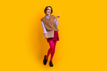 Photo portrait of attractive young woman netbook look point empty space dressed retro office clothes isolated on yellow color background