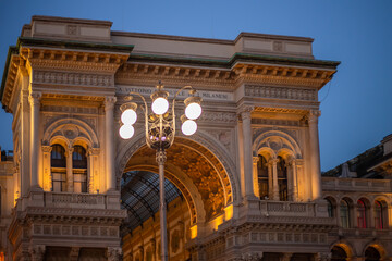 Fototapeta na wymiar Galleria Vittorio Emmanuel Passage, main entrance to a luxury shopping center evening time. Italy, Milan