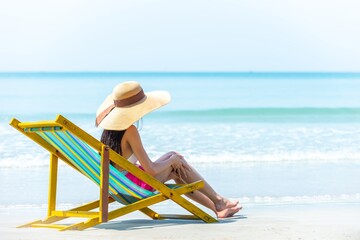 Happy Asian woman relax and enjoy outdoor lifestyle travel nature ocean on summer holiday vacation. Attractive girl applying moisturizing sunblock body lotion at tropical island beach in sunny day.