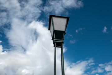 Poste antigo de iluminação pública com um bonito céu azul e algumas nuvens de fundo
