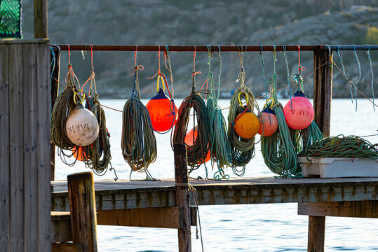 Multiple fishermen bouys and ropes hanging on pier.