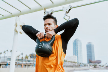 Young man training at the beach in the morning. Athlete exercising with sport equipment outdoor.