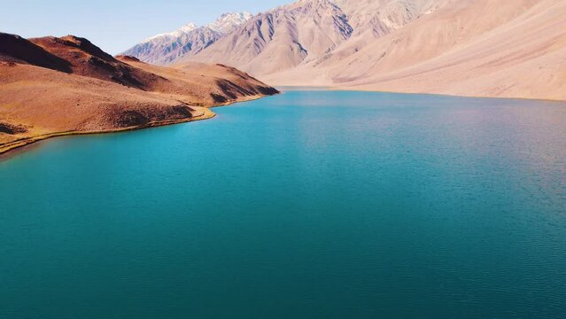 4K aerial shot of Camera goes up and revealing beautiful view of Chandratal lake in Himalaya mountains at Spiti Valley, India. Blue water of mountain lake. Calm and Scenic beauty of nature. 
