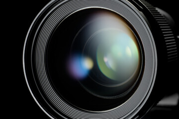 Photo or video camera lens with reflections close-up on the black background.