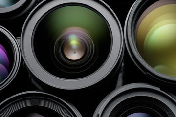 Bunch of black camera lenses with colorful reflections.