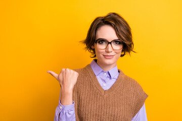 Portrait of clever woman with bob hairdo wear knit waistcoat indicating at discount empty space isolated on yellow color background