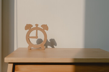 Photo of wooden clock shape design, showing watch model shadow, putting on wood chair with sunlight in room.