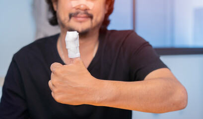 Shot image of Asian man show his fingers in a bandage, finger injury in a man, thumb gauze bandage.