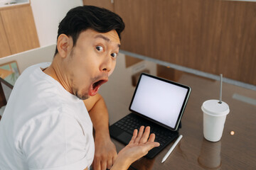 Asian man smiling, wow face, hand presenting white blank screen of laptop, got some idea, great choice, working and sitting in cafe.