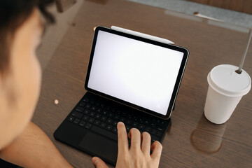 Back view of laptop showing white blank screen while man's hand typing keyboard, a cup of coffee putting on table. freelance concept.