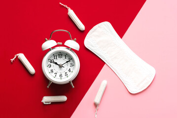 Top view of sanitary pad, menstrual tampons and white alarm clock. Concept of menstruation and menopause