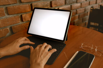 Back side view of woman hand using laptop and typing keyboard, showing white blank screen, working as freelance in cafe alone. 