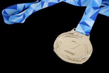 Silver medal with blue ribbon isolated on black background.	