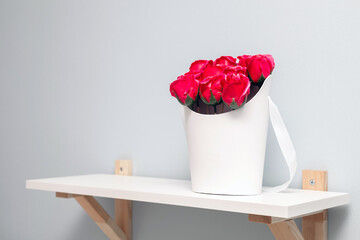 a box of red roses stands on a shelf.